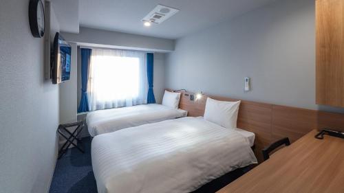 a hotel room with two beds and a window at Toyoko Inn Koriyama in Koriyama