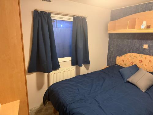 a bedroom with a blue bed and a window at sea view caravan park in Ingoldmells