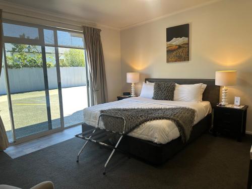 a bedroom with a bed and a large window at Two Tree Motel & Lodge in Blenheim