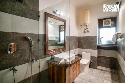 a bathroom with a sink and a toilet and a mirror at StayVista at Cedar Crest Villa with Bonfire, Valley View in Kasauli