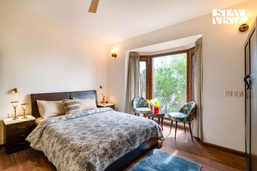 a bedroom with a bed and a large window at StayVista at Cedar Crest Villa with Bonfire, Valley View in Kasauli