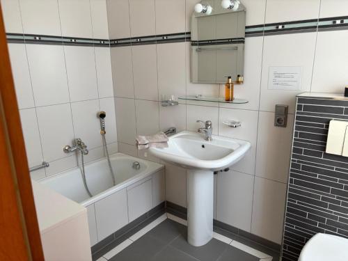 a white bathroom with a sink and a bath tub at Ferienwohnung Waldliebe in Waldkirchen