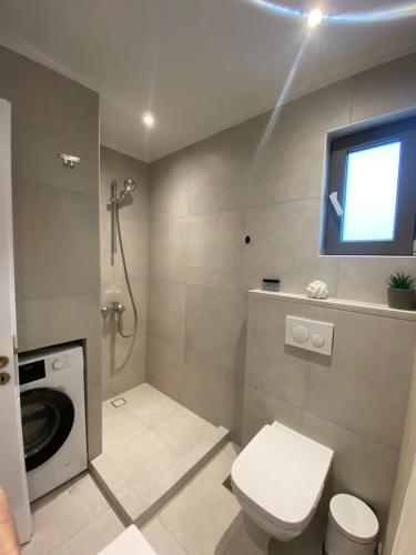 a bathroom with a washing machine and a toilet at The Costa Suite byArtistunknown in Vari