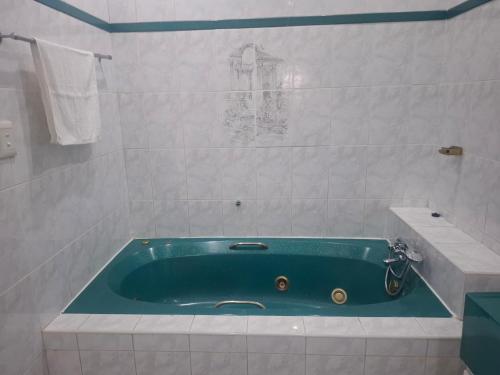 a bathroom with a turquoise bath tub with a sink at Nomty House in Durban