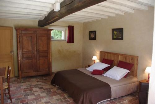 a bedroom with a large bed with red and white pillows at Jardin Solstice in Vaupillon