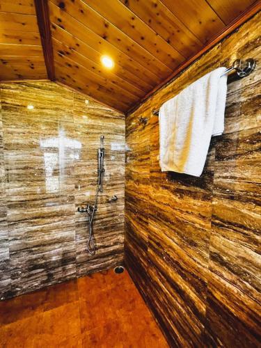 a bathroom with a shower and a towel on a wall at Nirvana Rooms - Shimla in Shimla