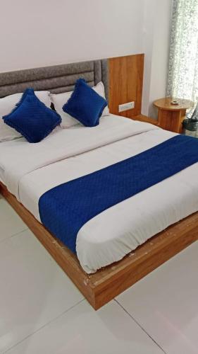 a bed with blue pillows on top of it at Hotel Vinayak Naroda in Ahmedabad