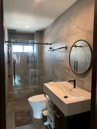 a bathroom with a sink and a toilet and a mirror at Thaiger House Studios in Bangkok