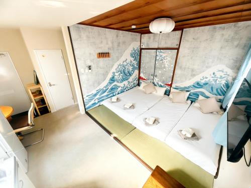 a room with a bed with a wave mural on the wall at Court Ada -1min to Araiyakushi-mae Station, 9min train to Shinjuku- 新井薬師前駅徒歩50秒 in Tokyo