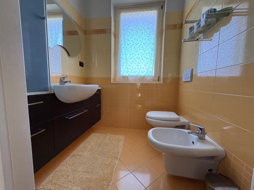 a bathroom with a sink and a toilet and a window at Casa Emma in Torre Pellice