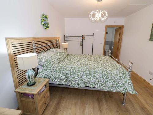 a bedroom with a bed and a table with a lamp at The Barn in Redditch