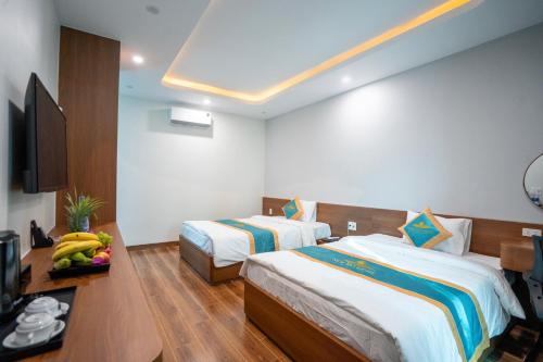 a hotel room with two beds and a television at New Sky Light Villa in Dong Hoi