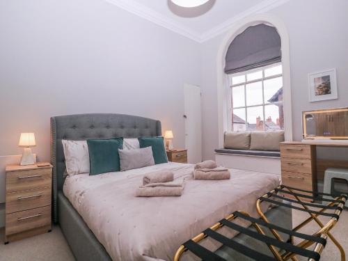 a bedroom with a large bed with a desk and a window at Stylish Town Apartment in Ross on Wye