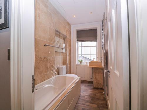 a bathroom with a bath tub and a window at Stylish Town Apartment in Ross on Wye