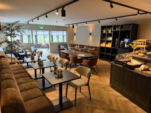 a restaurant with tables and chairs in a room at Hotel het Uilenbos in De Koog