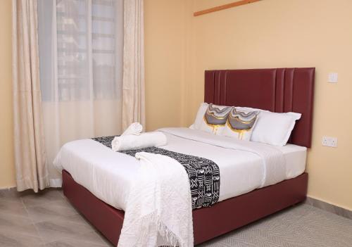 a bedroom with a large bed with white sheets at Gee Homes and Stays in Nyahururu