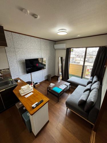 a living room with a couch and a table at Stay Plus Azunoa in Oyama