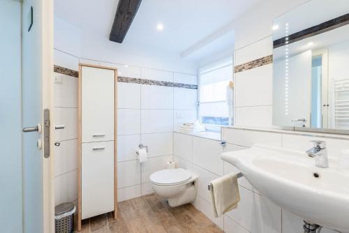 a white bathroom with a toilet and a sink at Ferienhaus Achtern Diek in Hemme