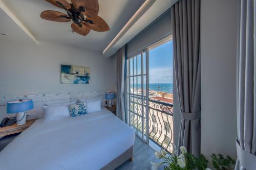 a bedroom with a bed and a balcony with the ocean at Solaro Hotel & Spa Phu Quoc - Sunset Town Seaview & Fireworks in Phú Quốc