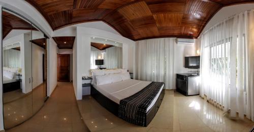a bedroom with a large bed with a wooden ceiling at Villa Perle Noire in Ambatoloaka