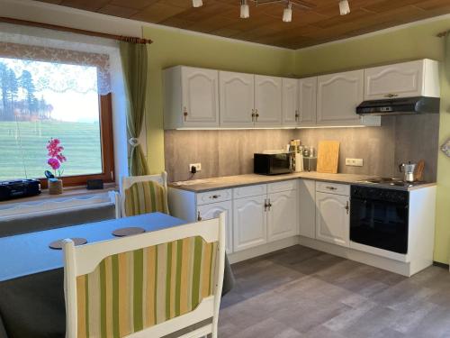 a kitchen with white cabinets and a blue table at Huber Hof in Oberrosenauerwald
