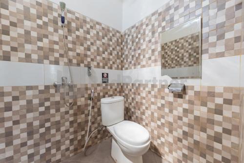 a bathroom with a toilet and a mirror at Wisma Brata 2 Mitra RedDoorz in Nyomolong