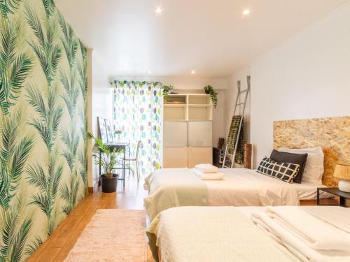 a bedroom with two beds and a wall with tropical wallpaper at Apartment in Oeiras Near Beach Easy Access Lisbon Cascais in Oeiras