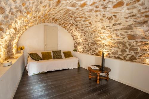 a bedroom with a bed and a stone wall at Maison de l'Orb in Cessenon