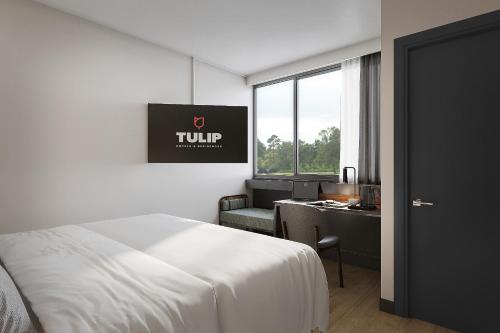 a hotel room with a bed and a desk and a window at Campanile Hotel & Restaurant Gouda in Gouda