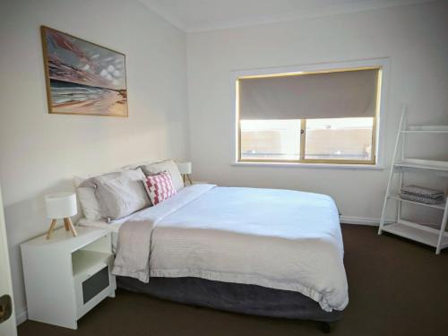 a white bedroom with a bed and a window at Waters Edge Retreat in Dawesville