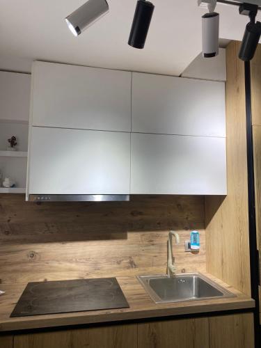 a kitchen with a sink and white cabinets at Redi Apartment Center in Elbasan