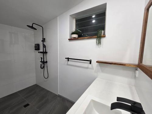 a white bathroom with a sink and a window at Hideaway Falls Rustic Farm House in Ravenshoe