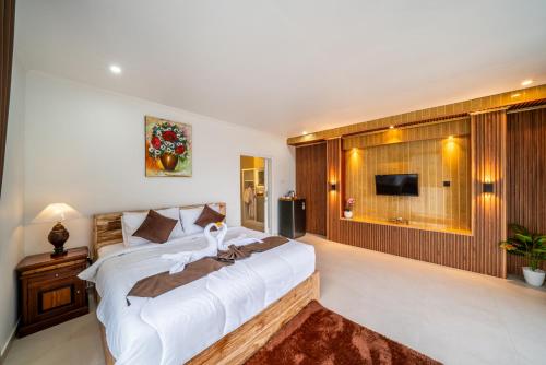 a bedroom with a large white bed and a television at Hayana Villa Kintamani in Gretek