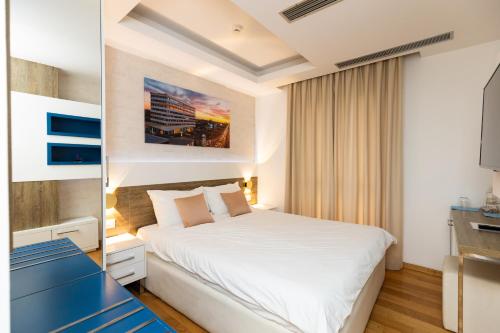a bedroom with a white bed and a blue bench at Rox in Modriča