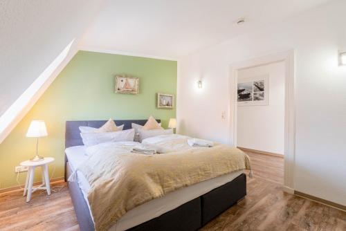 ein Schlafzimmer mit einem großen Bett und einer grünen Wand in der Unterkunft Hafencity Apartments in Tönning