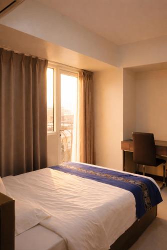 a bedroom with a bed and a window with a desk at Extremeli Suites in Manila