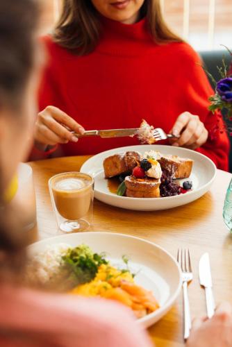 a woman sitting at a table with a plate of food at Zoku Vienna in Vienna
