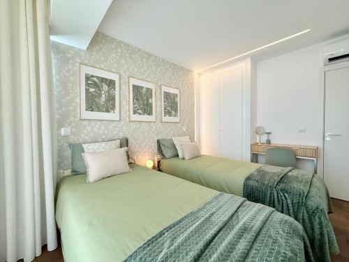 a bedroom with two beds and a desk with a window at Madeira Bliss II Prime Location with Pool and Parking in Funchal