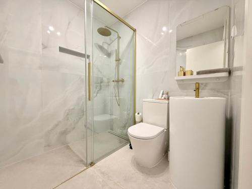 a white bathroom with a shower and a toilet at Madeira Bliss II Prime Location with Pool and Parking in Funchal