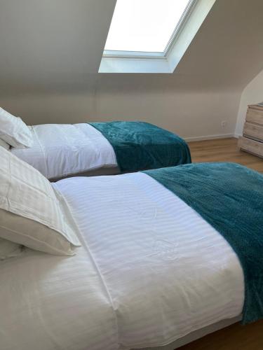 two twin beds in a room with a window at La Maison De Parrain in Kerlouan