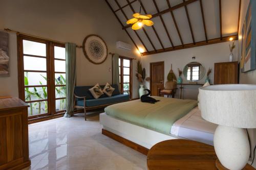 a bedroom with a bed and a couch and windows at The Swan Villa in Gili Trawangan
