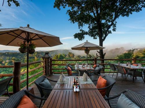 a wooden deck with tables and chairs and umbrellas at Katiliya Mountain Resort And Spa in Mae Salong Nai