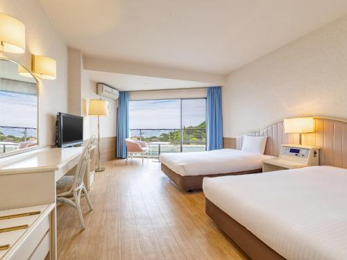 a hotel room with two beds and a television at Wan Wan Paradise Izukogen in Ito