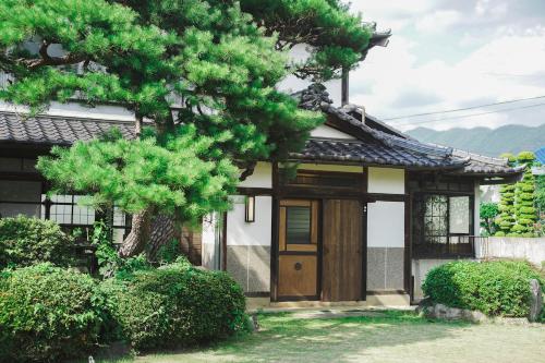 a small house with a tree in front of it at 古民家宿るうふ 蔦之家 Heritage Villa LOOF Tsutanoie in Koshu