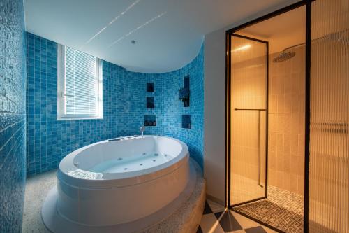 a bathroom with a tub and a shower with blue tiles at Solaro Hotel & Spa Phu Quoc - Sunset Town Seaview & Fireworks in Phú Quốc
