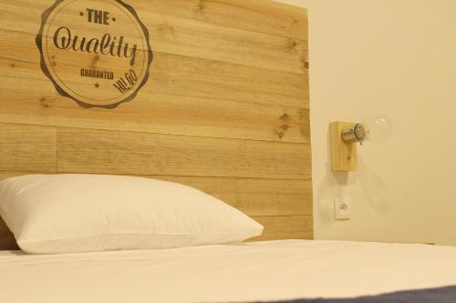 a bed with a wooden headboard and a white pillow at HI!GO in Vila Nova de Famalicão