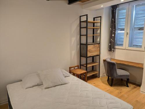 a bedroom with a bed and a chair next to a window at Duplex sur la mer in LʼÎle-Rousse