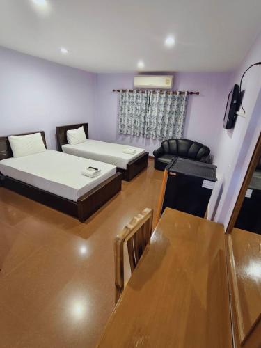 a living room with two beds and a couch at โรงแรมโกลเด้นอินน์ in Chachoengsao