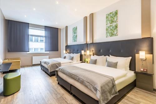 a hotel room with two beds and a desk at Garner Hotel Bremen City by IHG in Bremen