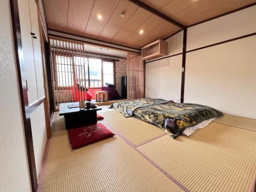 ein Schlafzimmer mit einem Bett mitten im Raum in der Unterkunft 阿蘇扇温泉 おおぎ荘 in Minamioguni